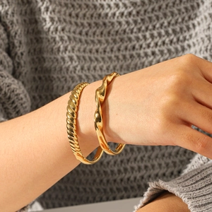 Bracelet torsadé en acier inoxydable plaqué or 18 carats et jonc cœur sur le poignet