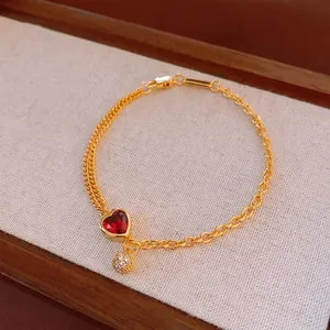 Elegant gold-plated heart bracelet with a red gemstone and pavé crystal charm on a mixed chain