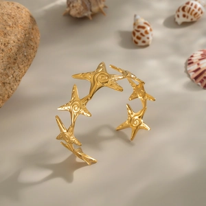 Close-up of golden starfish cuff bracelet with detailed texture on warm beach background