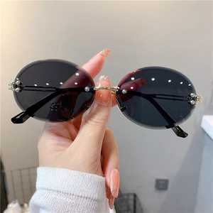 Détail de lunettes de soleil ovales sans monture avec verres dégradés noirs et charnières dorées