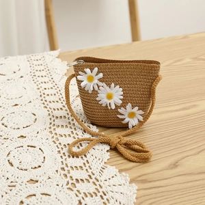Close-up of woven straw bag with white daisy flowers on wooden surface