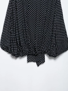 Detail of black polka dot blouse showing light fabric texture and knotted hem design