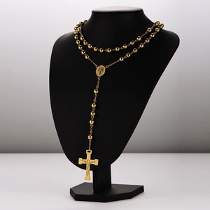 Golden rosary necklace with cross and medal pendant on a black bust display