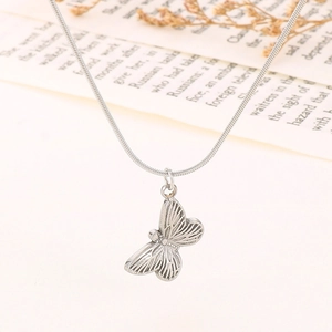 Elegant silver butterfly pendant necklace with sleek snake chain on a vintage book