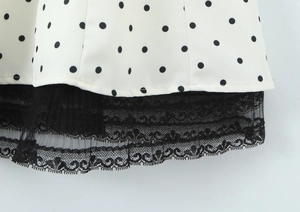 Close-up of white polka dot dress hem featuring elegant black lace trim detail