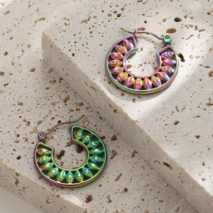 Macro shot of colorful hollow leaf pattern earrings in stainless steel on stone
