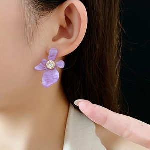Gros plan d'une boucle d'oreille fleur en résine violette avec zircone sur mannequin