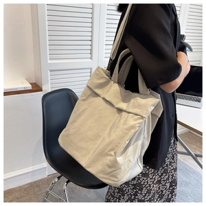Minimalist beige nylon tote bag shown in a professional lifestyle indoor setting