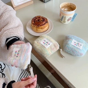 Close-up of a plush macaron color makeup bag with zipper and woven brand label