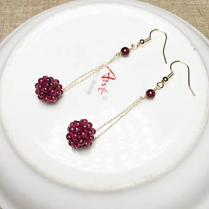 Detail view of handmade garnet beaded ball drop earrings with 14K gold-plated chains