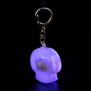 Close-up of a purple glowing skull keychain with LED light and metal lobster clasp