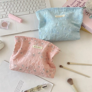 Detailed macro view of pink and blue floral jacquard makeup bags with Sozakka logo