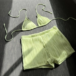 Flat lay of light green two-piece bikini featuring textured fabric and high waist shorts