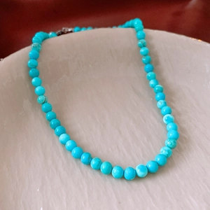 Détail macro de perles de turquoise avec texture naturelle sur un plateau en céramique