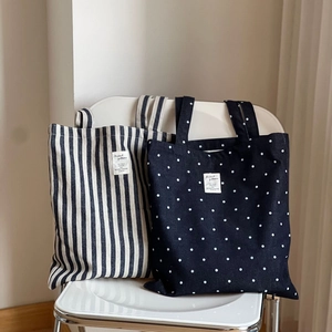 Détail de sacs fourre-tout en denim à pois et rayures sur une chaise minimaliste