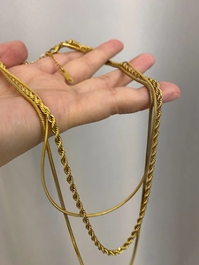 Detailed close-up of triple-layered 18K gold-plated snake and twisted rope chain necklace