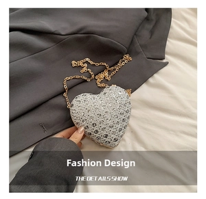 Close-up of heart-shaped sequin evening bag with silver crystals and a gold chain strap