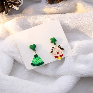 Macro view of asymmetrical Christmas earrings with a green beanie and cartoon elk