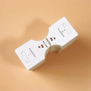 White cardboard hair accessory display cards with cherry print on peach background