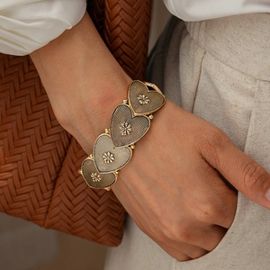 Detail of vintage gold heart-shaped metal bracelet with intricate floral relief textures