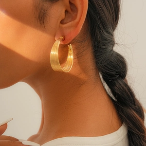 Detail von goldfarbenen Lagen-Creolen mit strukturiertem Multi-Ring-Minimal-Design
