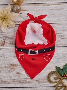 Close-up of a festive red Christmas dog bandana featuring a Santa Claus design on wood