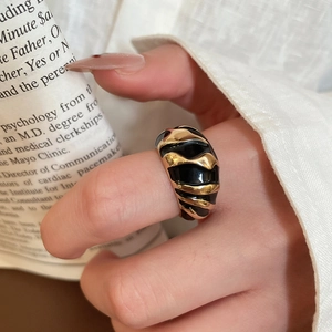 Detail shot of wide gold ring with black enamel wave textures on a vintage magazine