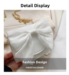White leather crossbody bag detail, featuring an elegant large bow and gold chain strap.