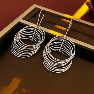 Detail view of multi-layered silver concentric circle earrings on a luxury display box
