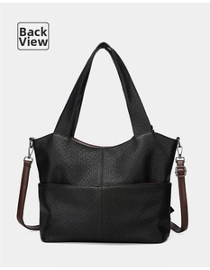 Detail view of the back of a black textured tote bag with contrast brown straps