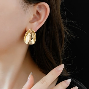 Close-up of irregular gold molten earrings on model with high gloss finish