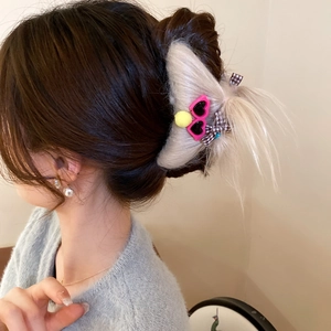 Detail of plush monster hair claw clip with pink heart glasses on a messy bun hairstyle