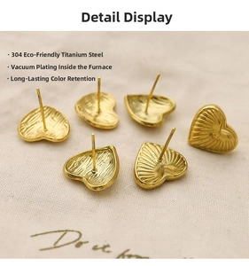 Detailed macro of 18K gold-plated 304 stainless steel heart stud earrings on linen