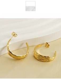 Macro detail of gold titanium steel hoop earrings with ripple lava texture on stone