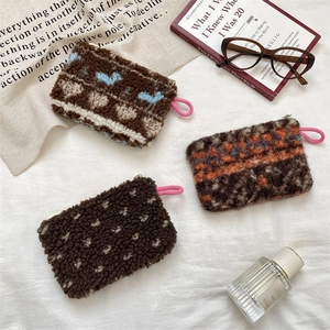 Detailed close-up of brown sherpa plush coin pouches with heart and dot patterns