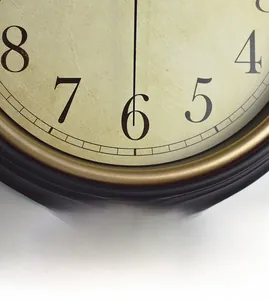 Detail of retro wall clock with vintage yellow textured dial and quartz movement numerals