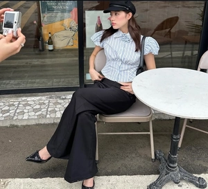 Detail of blue striped puff sleeve shirt paired with high waist trousers in a cafe setting