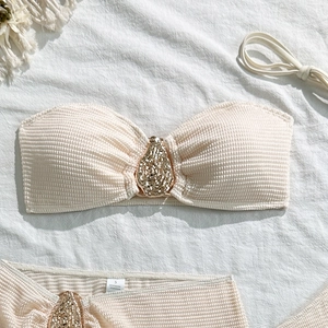 Detail of off-white bikini with waffle texture and large gold rhinestone teardrop