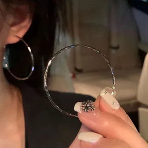 Detail of large silver textured hoop earrings with a faceted surface for a shimmering effect