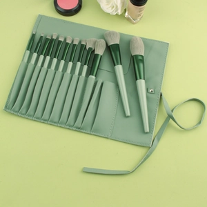 Flat lay of 14 mint green makeup brushes with soft gray bristles and a leather wrap case