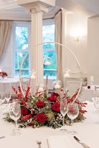 Close-up of white metal arch with glass globes and red rose floral decorations
