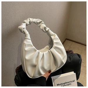 Detail of white pleated underarm bag with twisted handle and soft leather texture