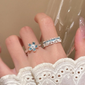 Close-up of blue floral and lace-style rings set on a hand with soft warm lighting