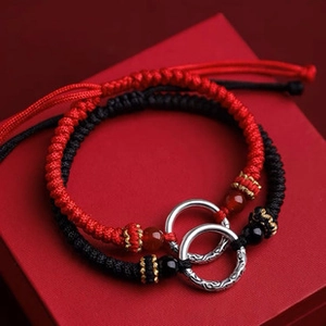 Macro shot of red and black braided friendship bracelets in a luxury red gift box