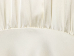Gros plan sur le tissu en satin blanc perle montrant la texture plissée et satinée