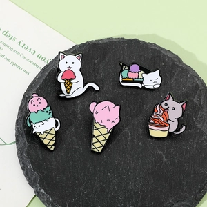 Detail view of five assorted enamel cat pins eating ice cream on black stone base