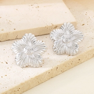 Detailed close-up of silver flower stud earrings with a polished metallic finish
