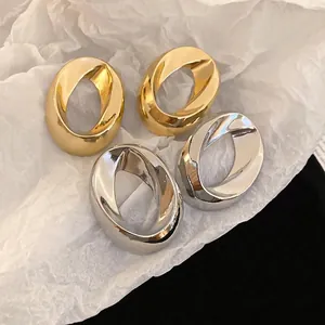Minimalist geometric twisted oval stud earrings in polished gold and silver finishes