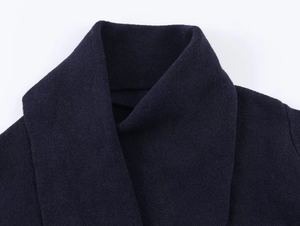 Close-up of the wide lapel collar and knitted texture of a dark blue short cardigan jacket