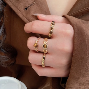 Detail view of vintage gold-plated tiger eye ring set on model wearing brown wool jacket